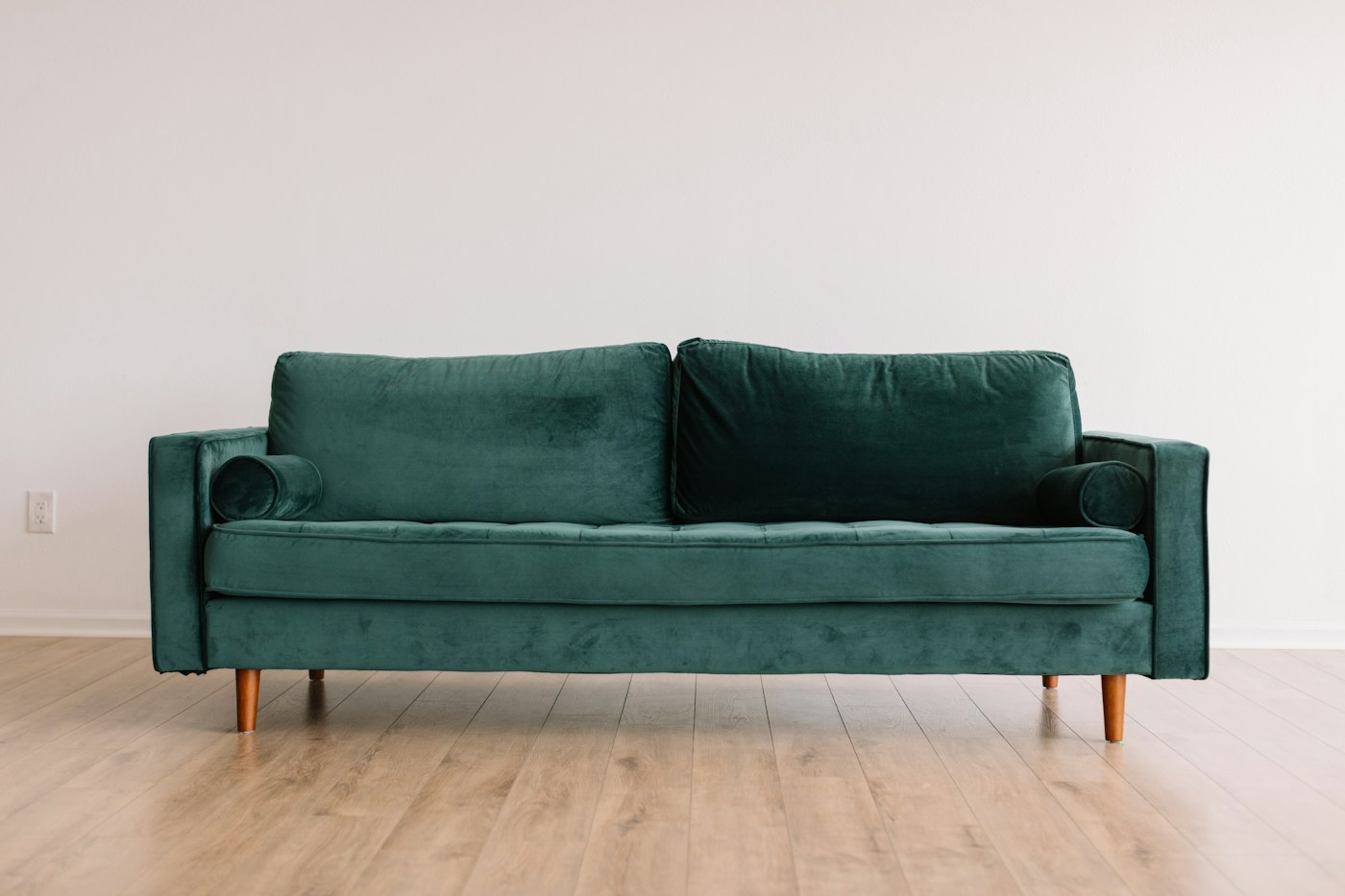 Deep green upholstered sofa with piped cushions